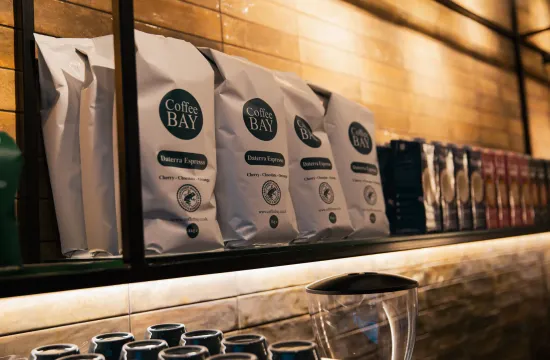 Bags of Coffee Bay Daterra Espresso beans lined up on a shelf above the coffee counter at The FIT Partnership cafe