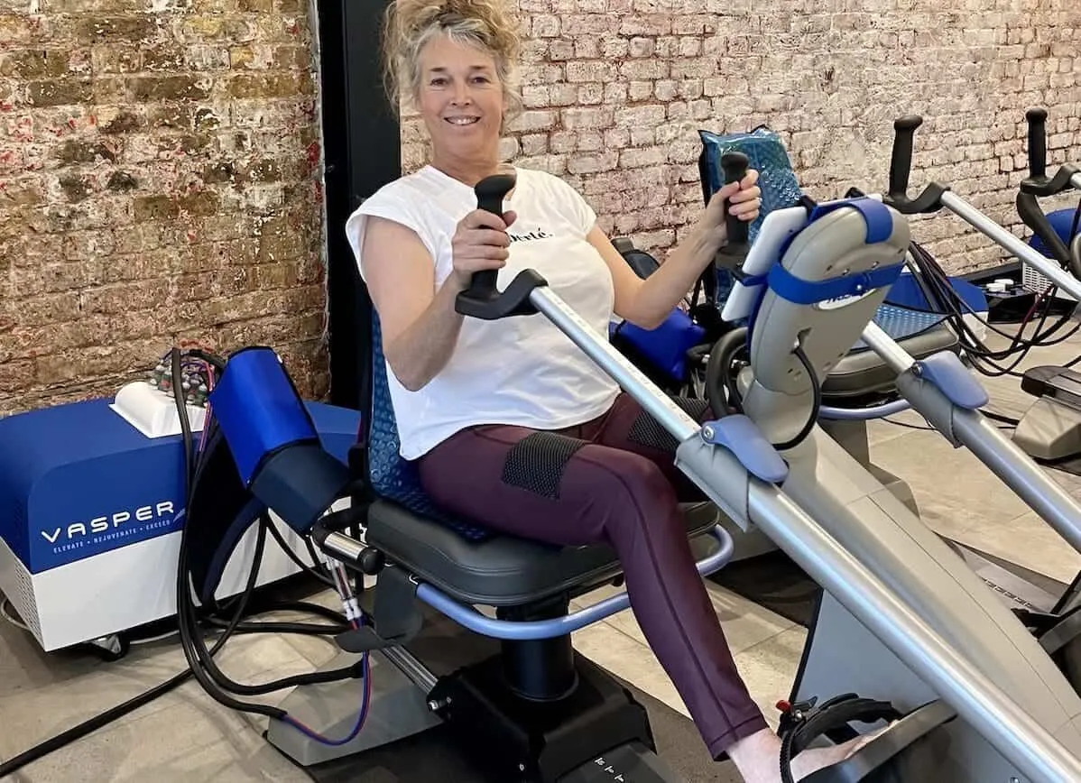 A smiling woman using the Vasper System machine at The F.I.T Partnership studio
