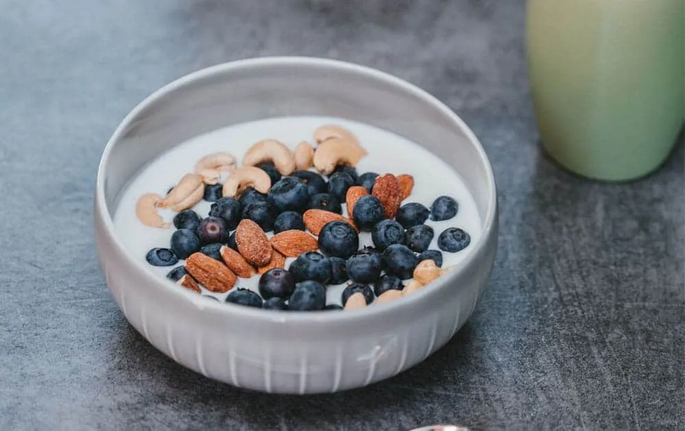 Bowl of natural yoghurt topped with blueberries, cashews and almonds