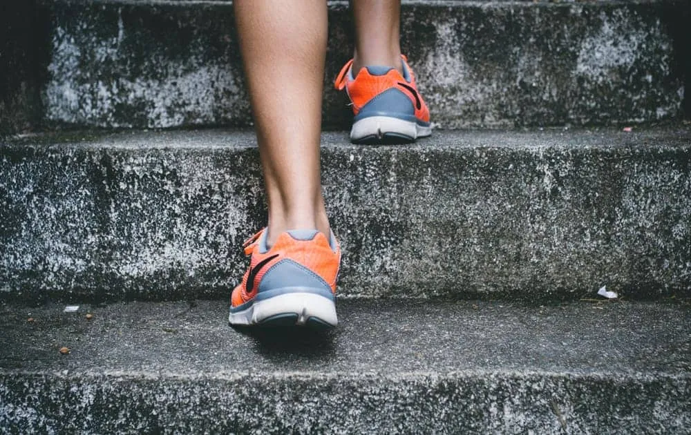 Close-up of legs and orange trainers walking up outdoor stone steps