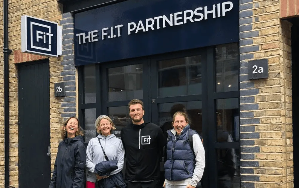 Four people smiling outside The F.I.T Partnership studio entrance