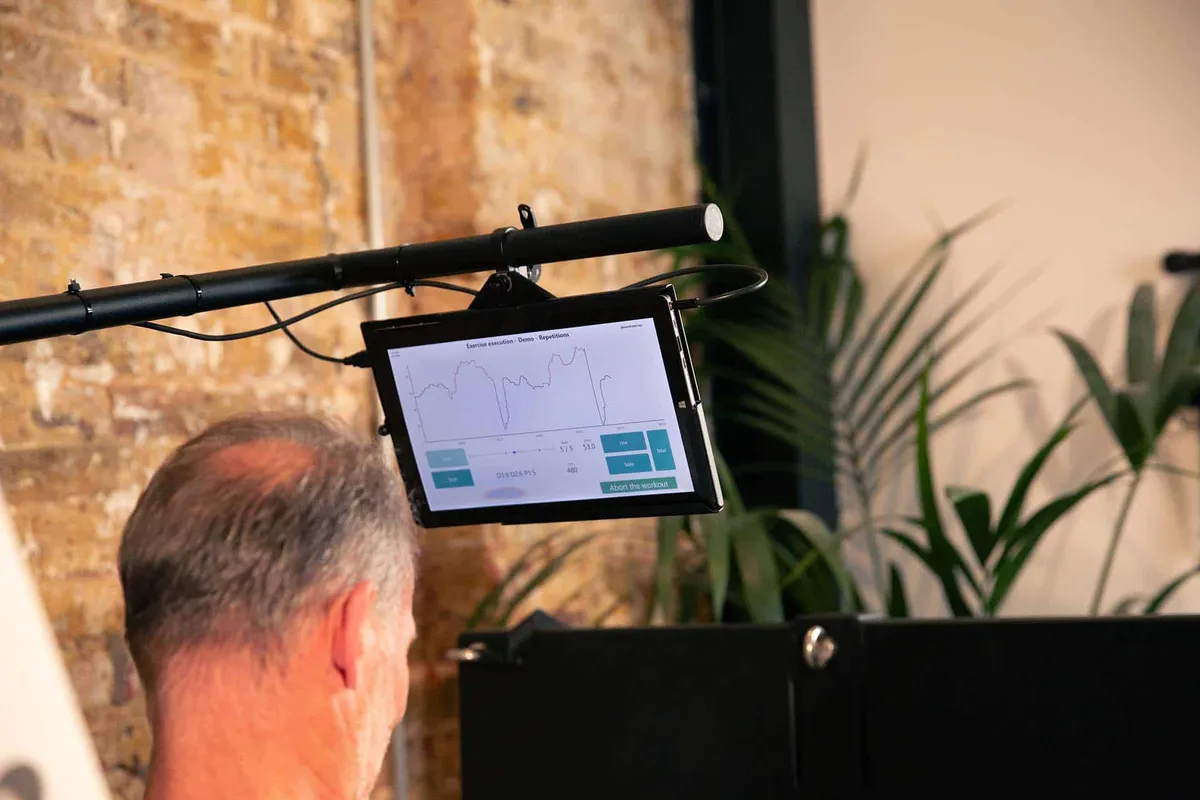 Man using a Balkan Strength exercise machine while viewing his repetition data on a screen