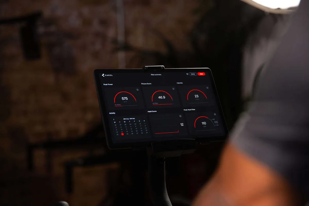 Tablet screen on an exercise bike displaying ride data including power, fitness score and heart rate