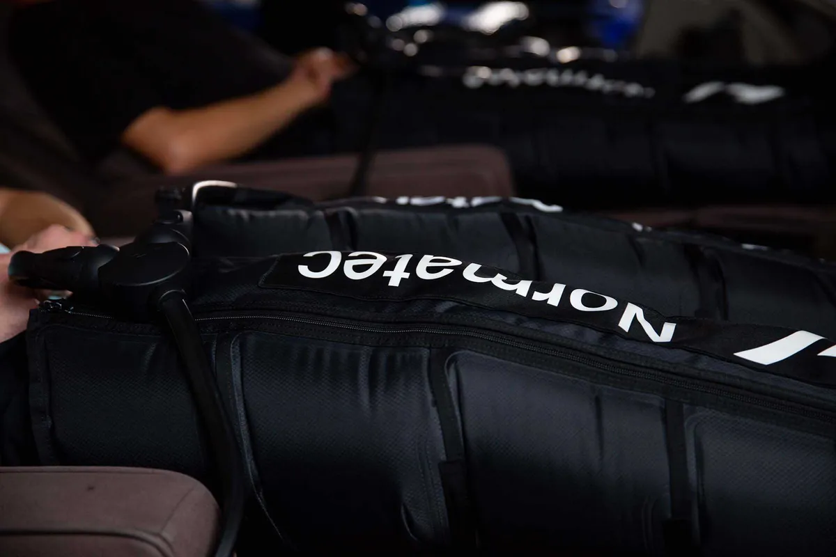Close-up of black Normatec compression therapy boots strapped around a pair of legs