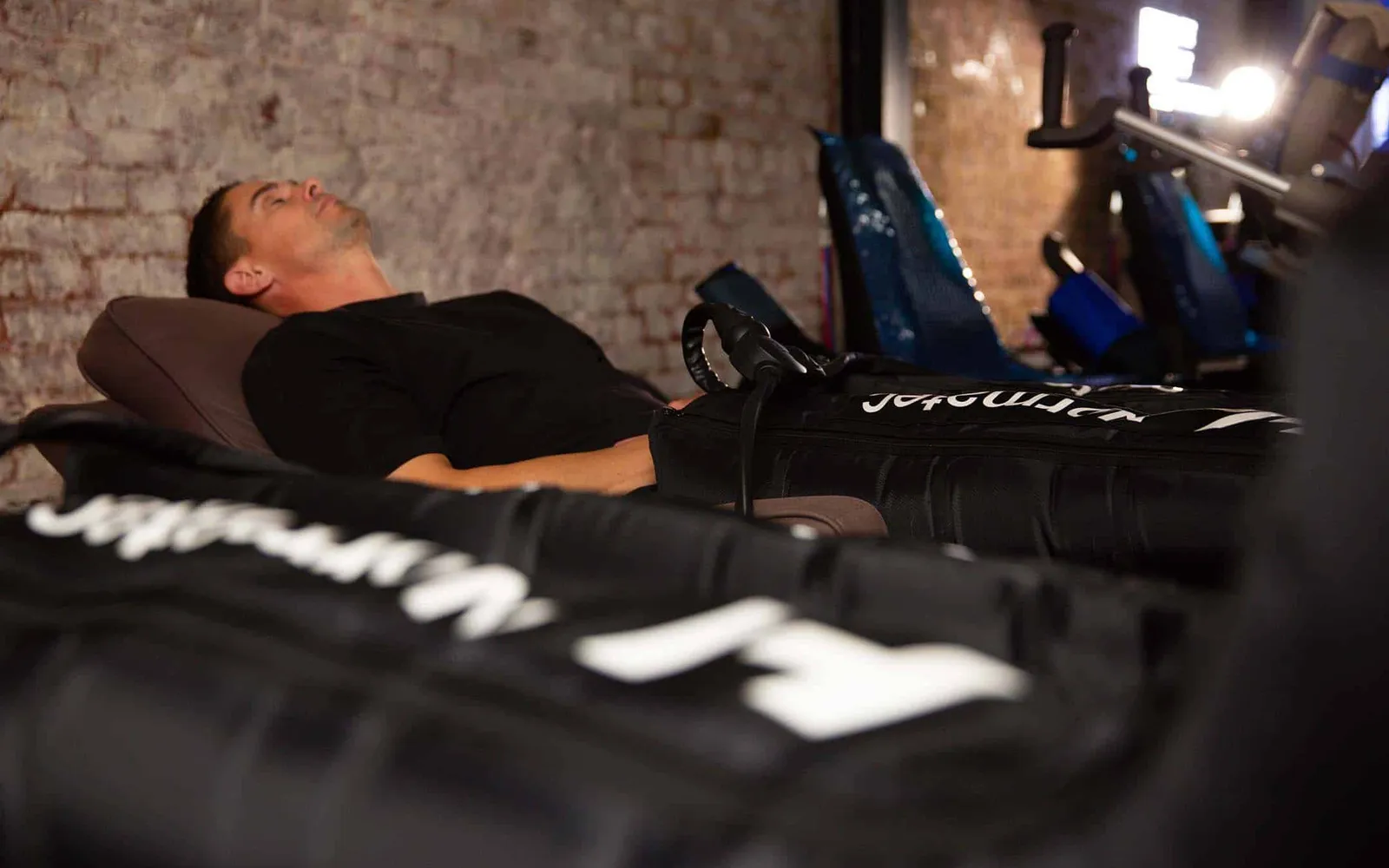 A man reclining with compression therapy boots fitted to his legs in a treatment room