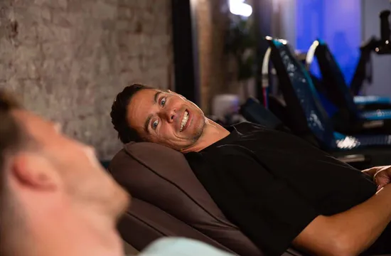 A man smiling while reclining with compression therapy boots fitted to his legs