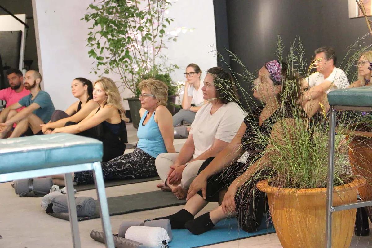 A group of people sitting cross-legged on mats during a studio wellness event