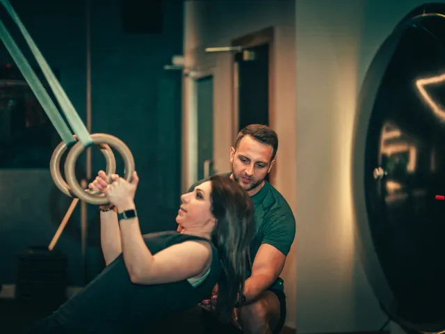 A FIT Partnership trainer coaches a member through an exercise on the gymnastic rings