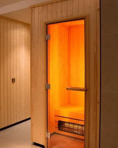 The open doorway of the infrared sauna cabin, glowing warm orange