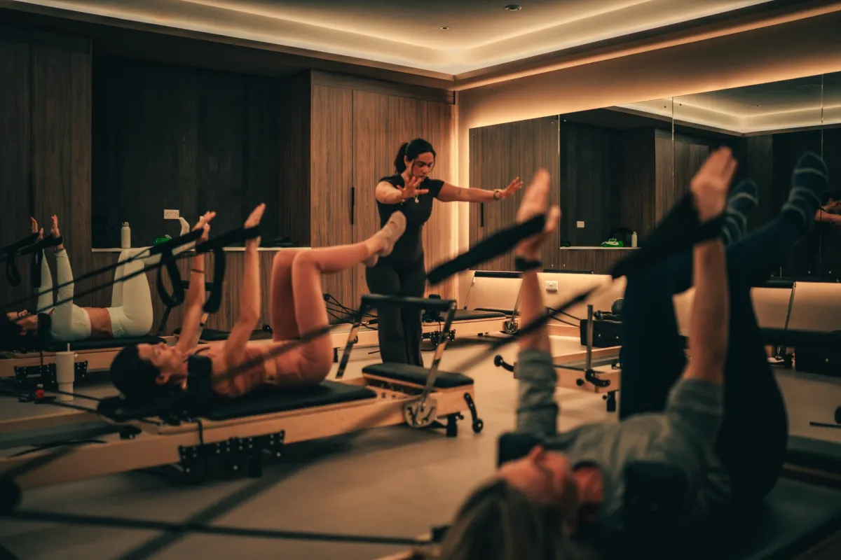 An instructor leads a small Reformer Pilates class in the studio at The FIT Partnership