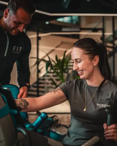 A trainer assists a member on a resistance machine during a Day Pass visit at The FIT Partnership