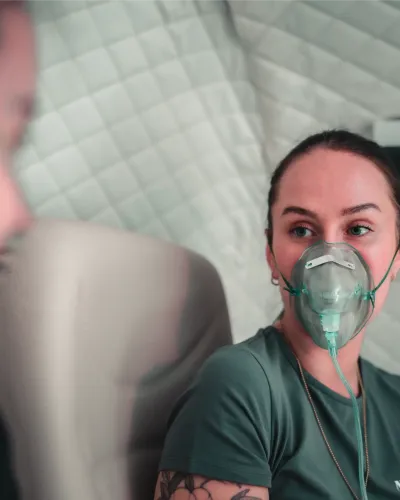 A woman relaxes wearing an oxygen mask during an introductory hyperbaric oxygen therapy session