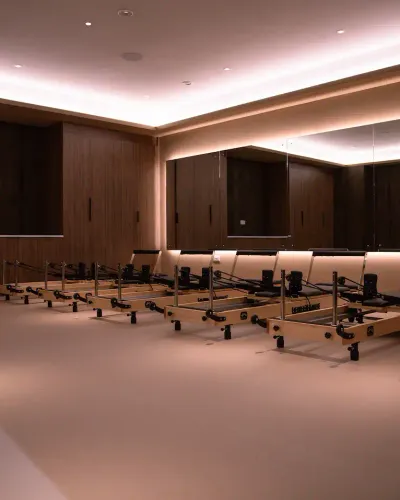 Rows of Pilates reformer machines line the mirrored studio at The FIT Partnership