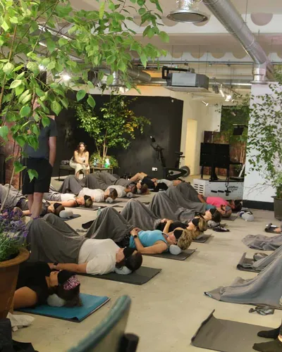 Class participants lie covered in blankets during a guided relaxation session surrounded by potted plants