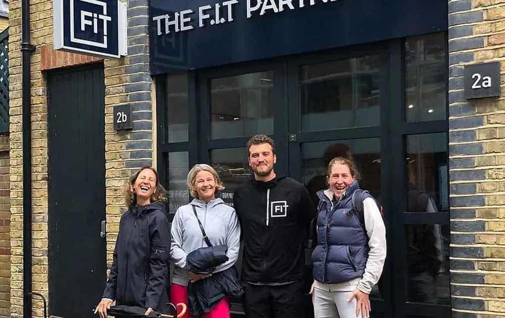 A group of smiling people pose outside The FIT Partnership studio entrance